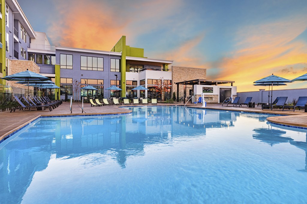 Resort style swimming pool at Zeta Apartments with buildings and sunset in the background Resort style swimming pool with buildings and sunset in the background at Zeta Luxury Apartments in Sacramento, CA