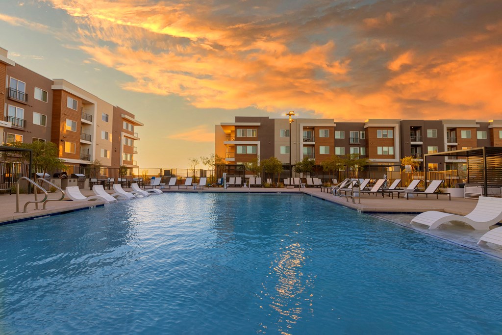 evening pool lounge area with chairs and a sunset in the background