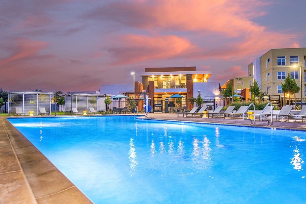 apartments swimming pool lounge area with apartment buildings in background at twilight apartments swimming pool lounge area with apartment buildings in background at twilight at Solasta, Sacramento, CA, 95831