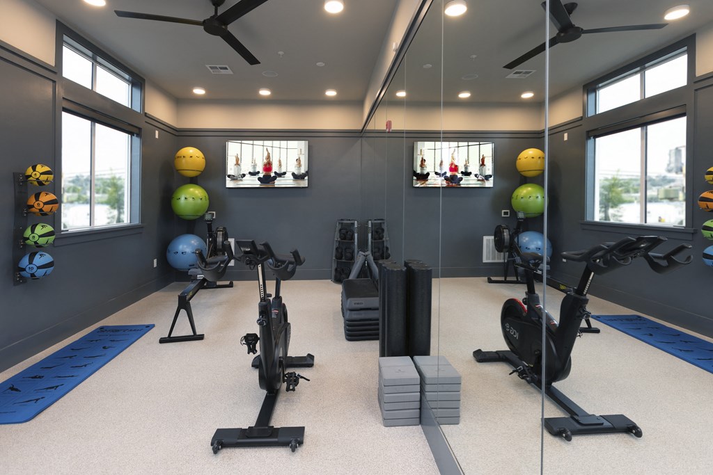 a gym with exercise balls and weights on the floor and windows