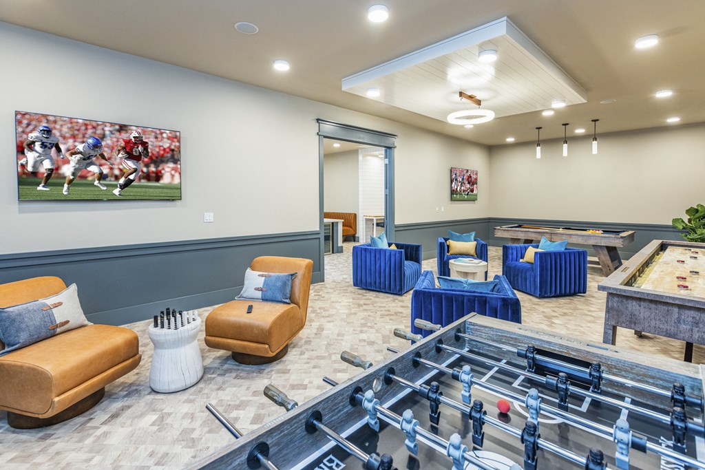 a game room with tables and chairs and a football game on the wall