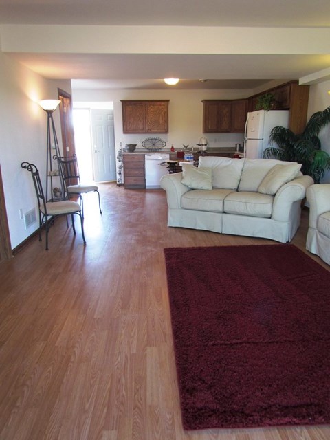 A living room with a white couch and a wooden floor.