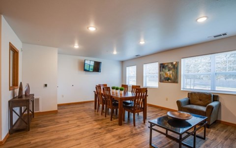 A living room with a wooden floor and a television mounted on the wall.