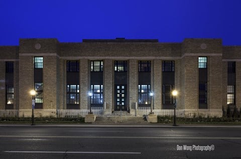 A building with a dark facade and lights on the windows and steps.