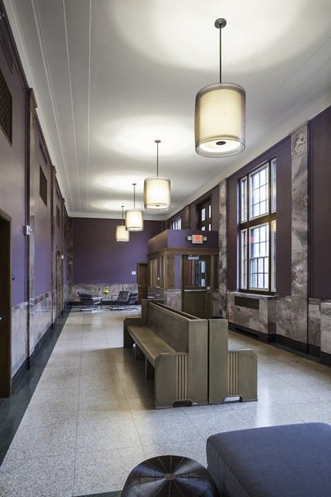 A long hallway with a bench and lights hanging from the ceiling.