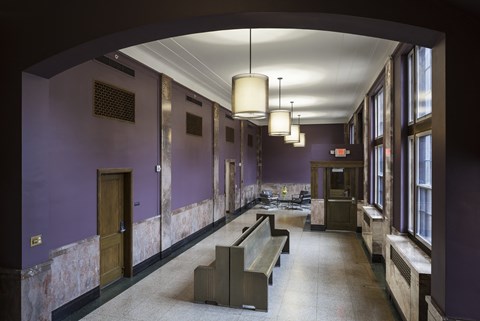 A long hallway with purple walls and a bench in the middle.