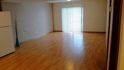 A room with wooden floors and a white refrigerator.