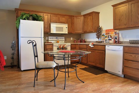 A kitchen with a white fridge, a glass top stove, and wooden cabinets.