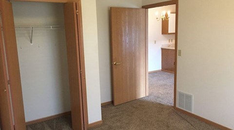 A room with a brown carpet and a wooden door.