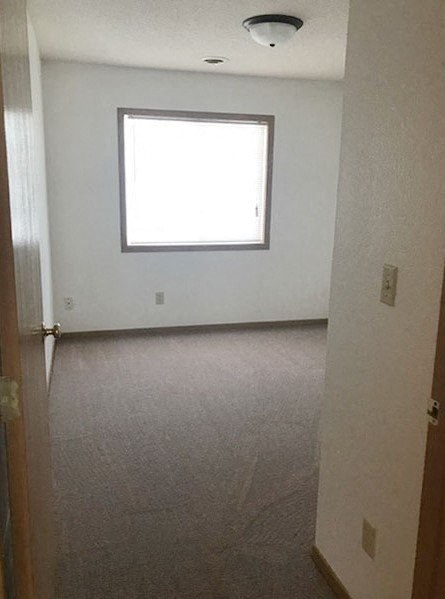 A room with a window and carpeted floor.
