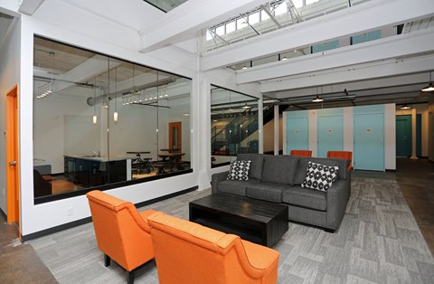 A modern living room with a grey couch and orange chairs.