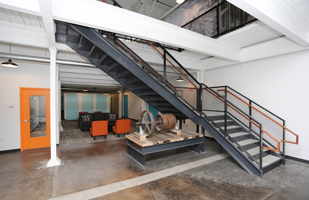 A staircase with orange handrails leads to a room with a large orange door.