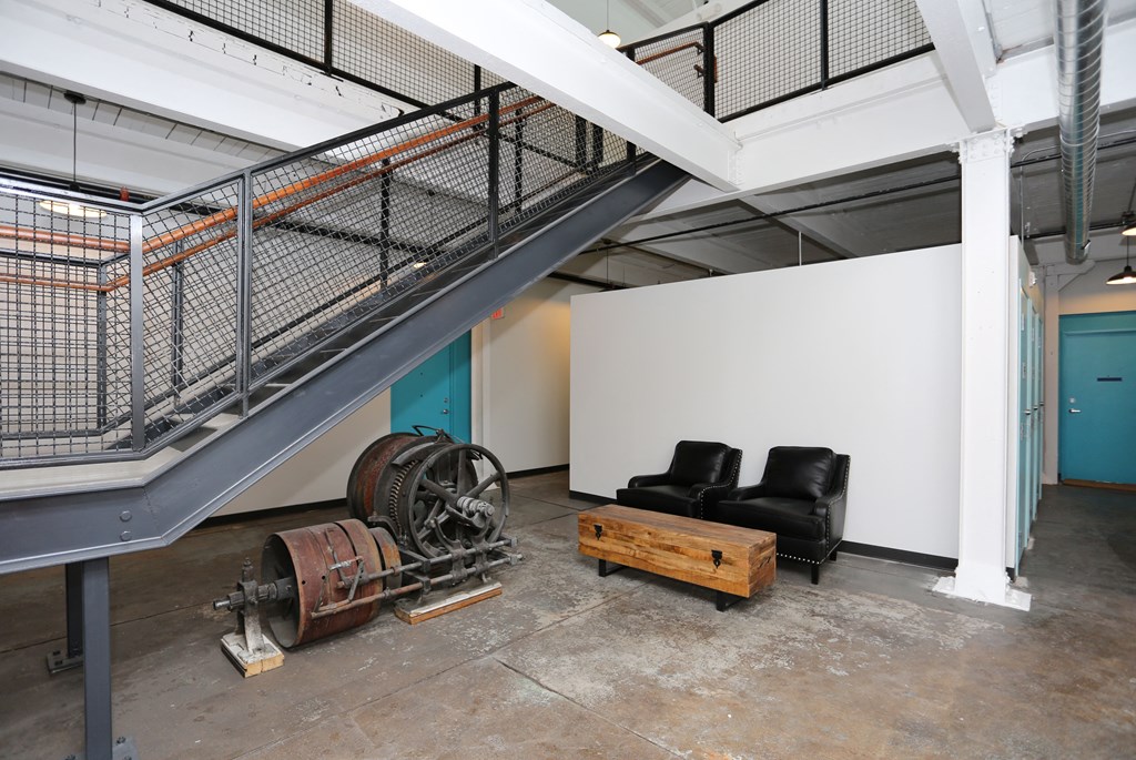 A room with a couch, a table, and a staircase.