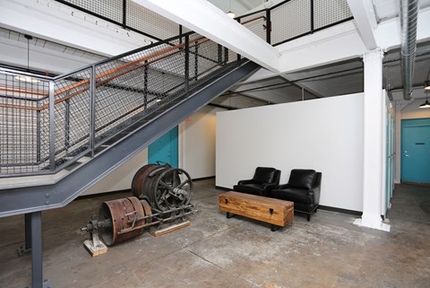 A room with a couch, a table, and a staircase.