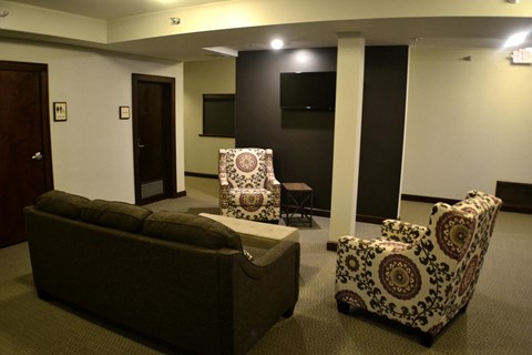 A living room with a couch, two chairs and a television.