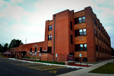 A red brick building with a parking lot in front.