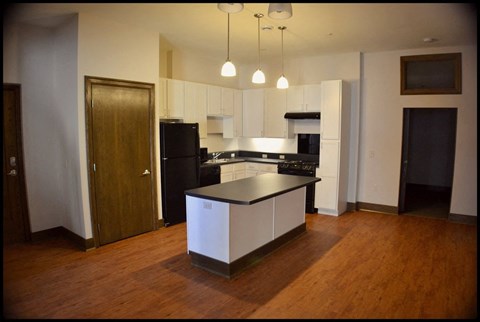 A kitchen with a black fridge and white cabinets.