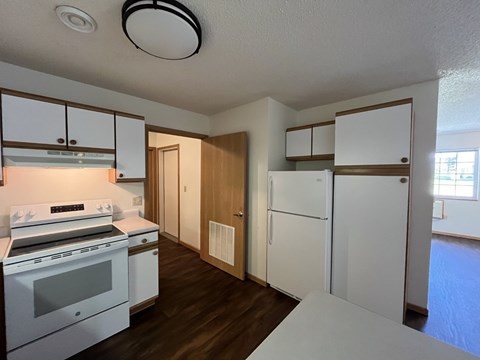 A kitchen with white appliances and wooden cabinets.