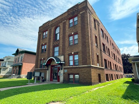 a tall brick building with a green lawn in front of it