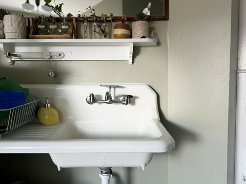 a white kitchen sink with a shelf above it