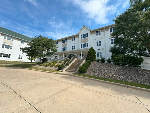 A large white building with a green roof and a stone pathway leading to the entrance.