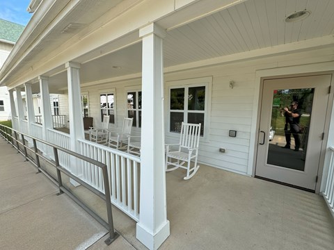 A white porch with a metal railing and chairs.