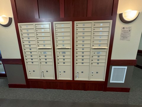 A wall of mailboxes is lined up against a wall.