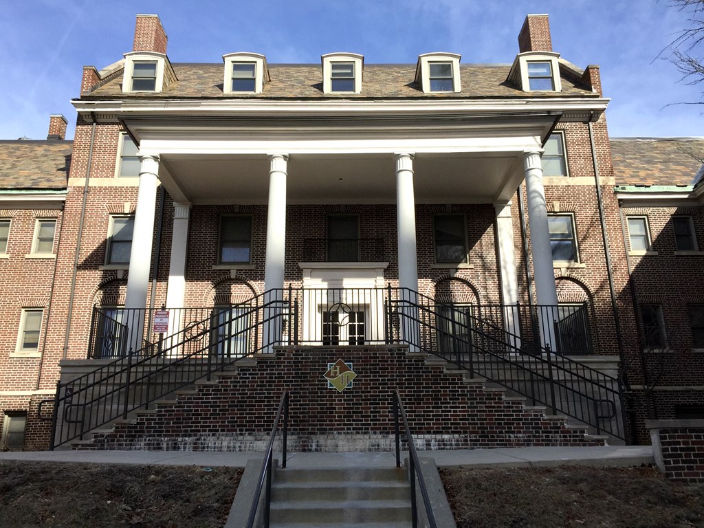 A large red brick building with a staircase leading to the front door.