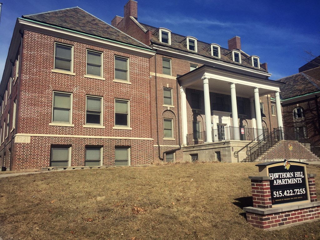 A brick building with a sign in front that says Hawthorn Hill Apartments.