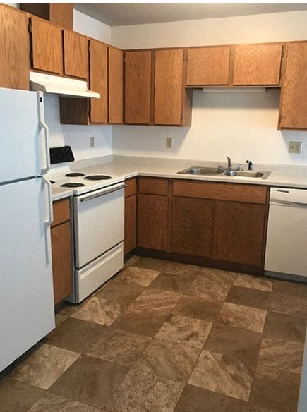 A kitchen with brown cabinets and a white refrigerator.