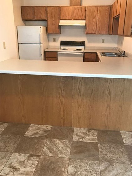 A kitchen with a white refrigerator and wooden cabinets.