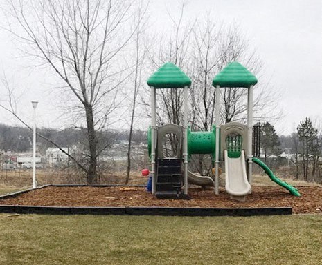 A playground with a green slide and two green tops.