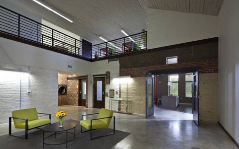 A room with a balcony, two chairs, a table, and a vase of flowers.