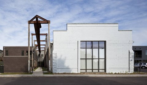 A white building with a large window and a wooden structure in front.