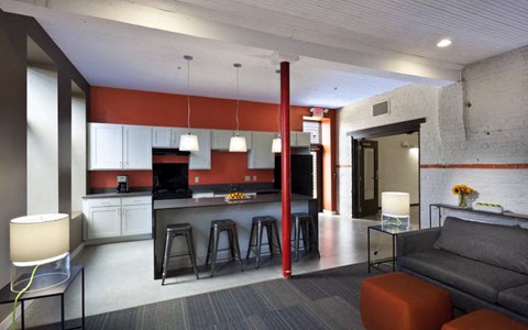 A modern kitchen with a bar area and a grey couch.