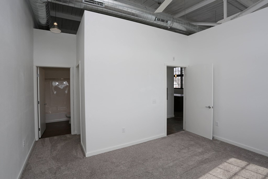 A room with a carpeted floor and a doorway leading to another room.