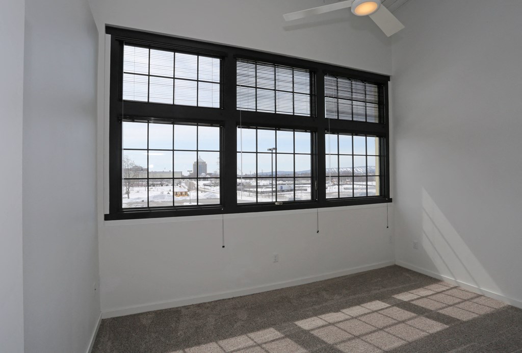 A room with a large window and a ceiling fan.