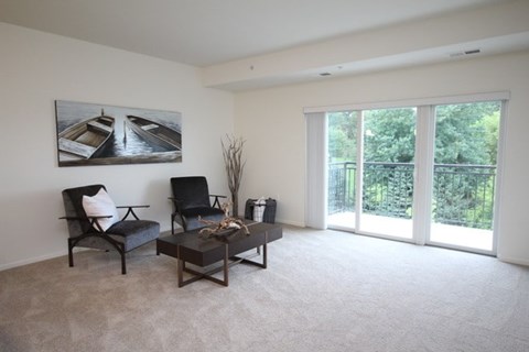 A living room with a grey couch, a black chair, a coffee table, and a painting of boats on the wall.