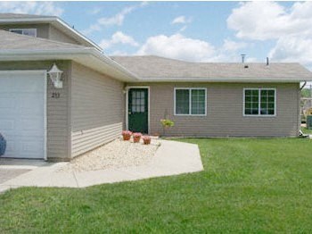 A house with a grey siding and a green door.