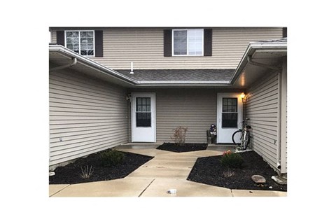 A house with a white door and a small garden in front.