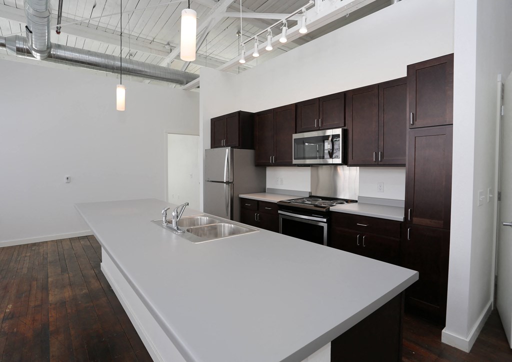 A kitchen with dark brown cabinets and a white countertop.