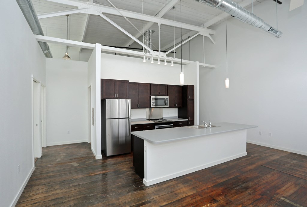 A kitchen with a white counter and wooden floors.