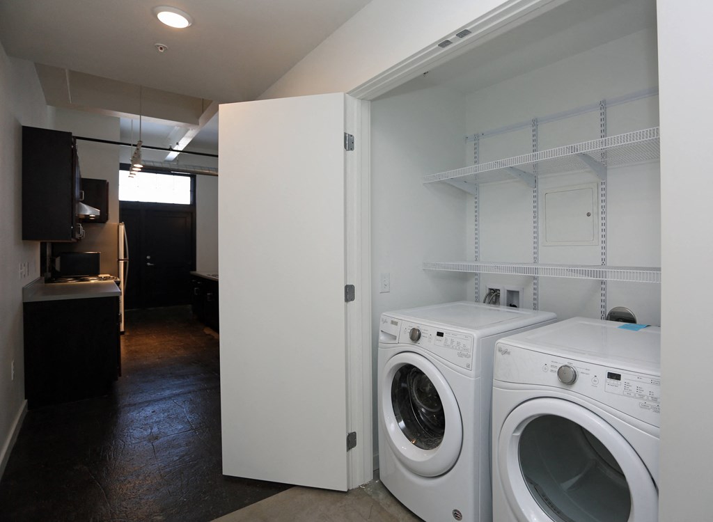 A laundry room with a white door open to a white dryer.