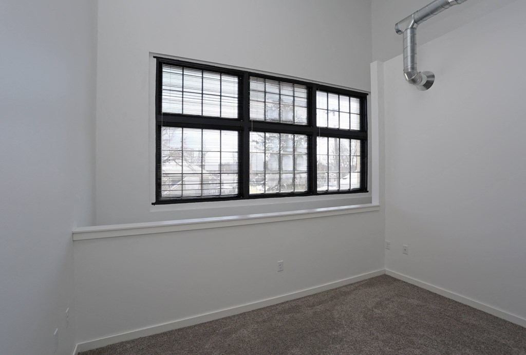 A room with a large window and a carpeted floor.