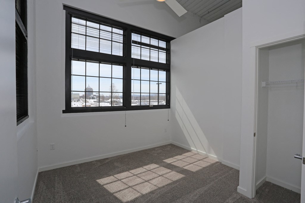 A room with a large window and a carpeted floor.