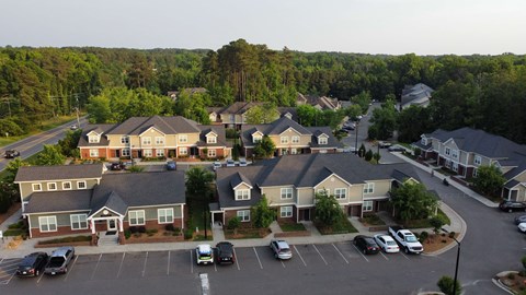 A parking lot in front of a building with cars parked.