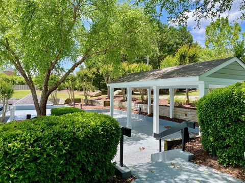 a pavilion with a seating area and a swimming pool in the background