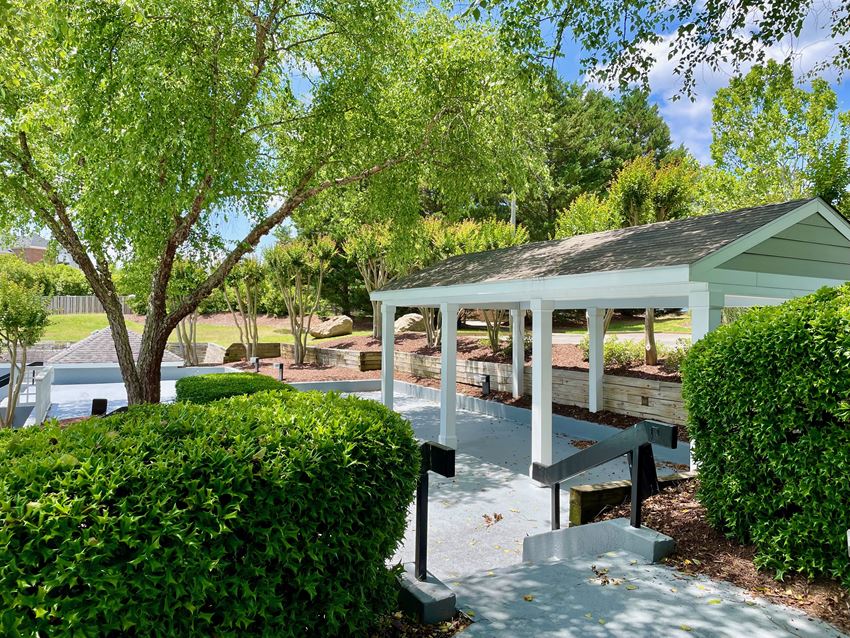 a pavilion with a seating area and a swimming pool in the background - Photo Gallery