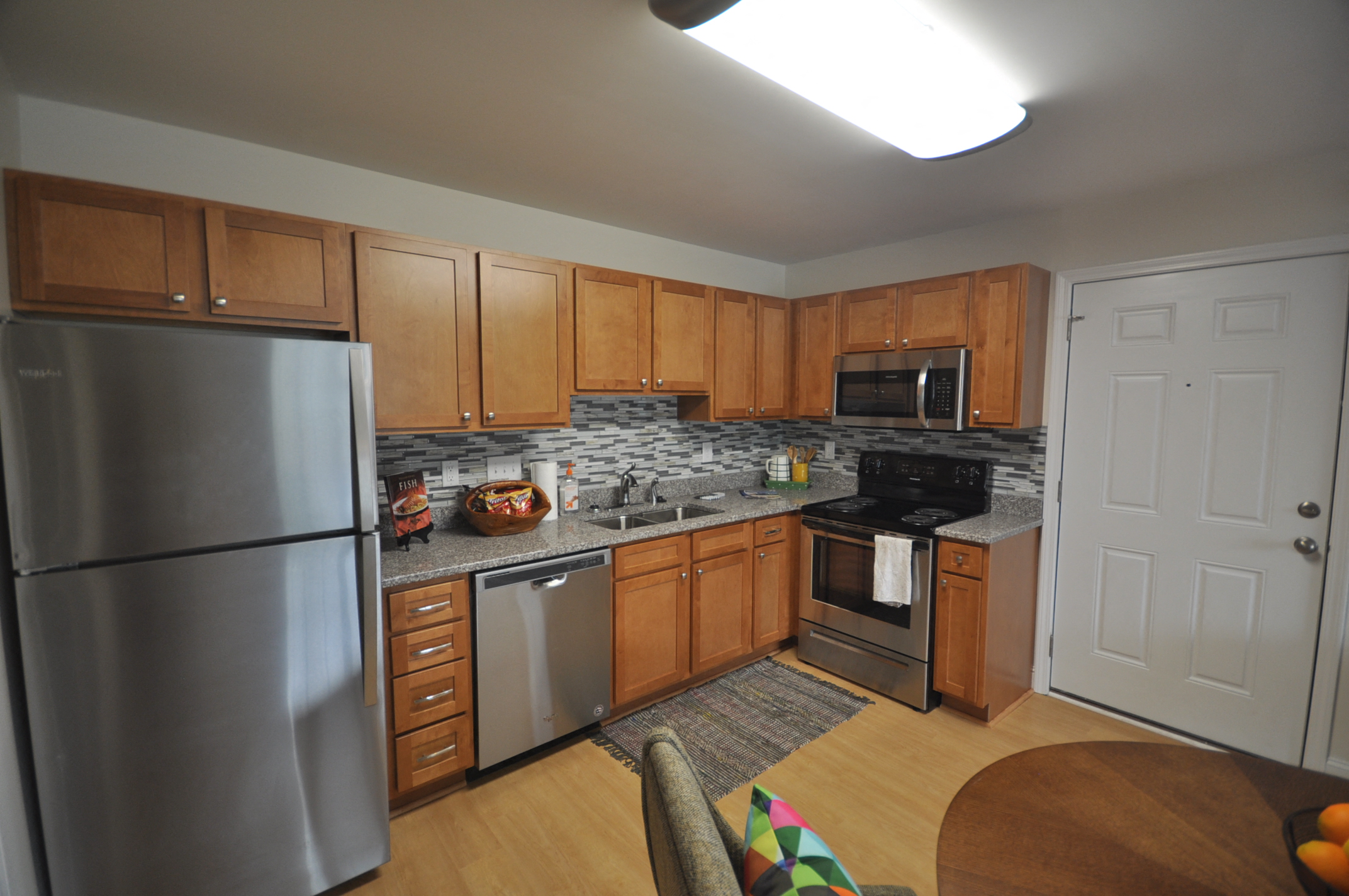 A kitchen with wooden cabinets and a stainless steel refrigerator.
