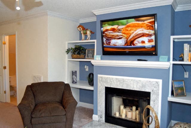 A living room with a fireplace and a television on the wall.